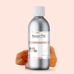 Bottle of Raasa Oils Amber Fragrance Oil with amber fruits on a light pink background