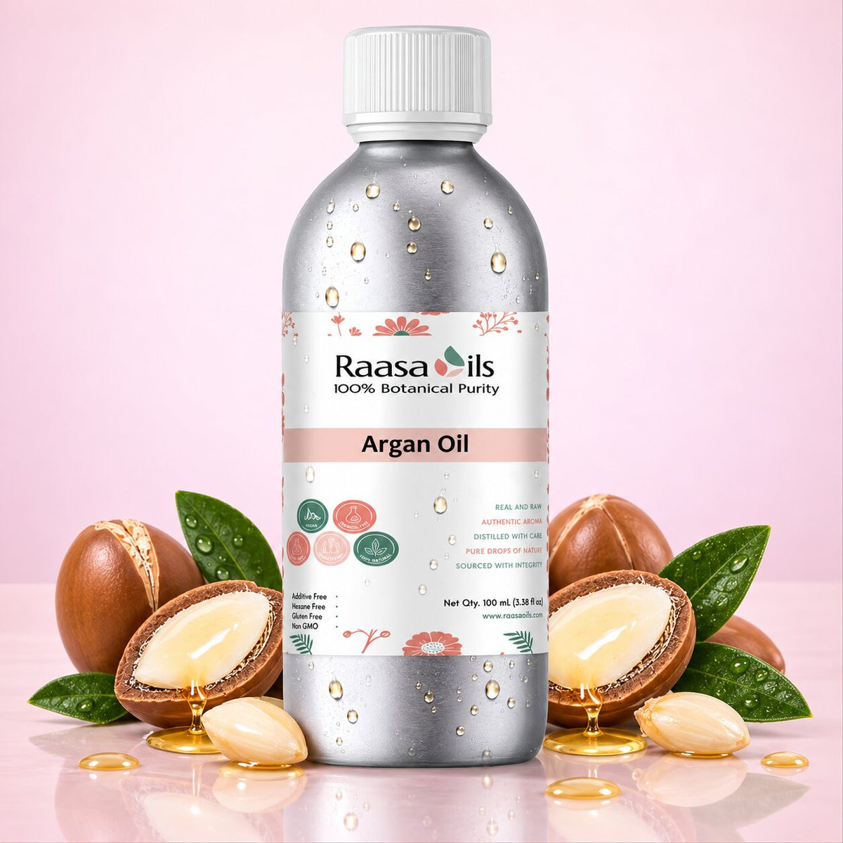 A bottle of Raasa Oils Argan Oil centered against a soft pink background, surrounded by whole and sliced argan nuts with visible golden oil and a few green leaves.