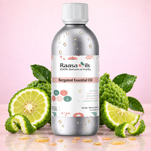 A bottle of Raasa Oils Bergamot Essential Oil centered on a pink background, surrounded by bergamot slices, bergamot fruit, and green leaves. The bottle is metallic silver with a white cap and a white label featuring pink and green botanical illustrations.