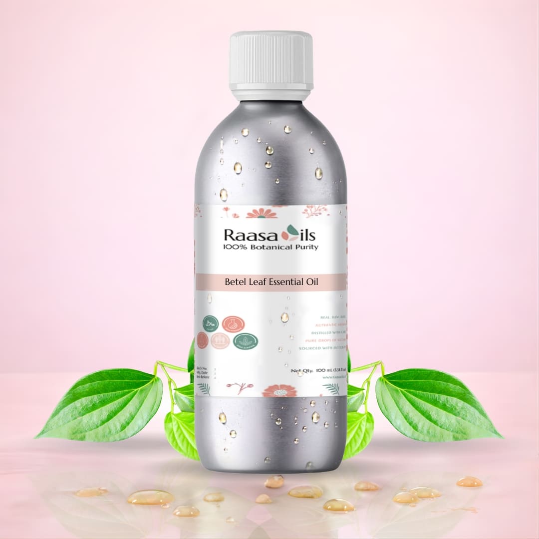 Bottle of Raasa Oils Betel Leaf Essential Oil with green leaves and seeds on a pink background
