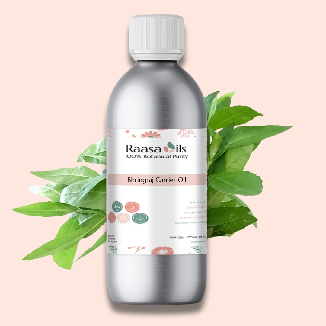 Bottle of Raasa Oils Bhringraj Carrier Oil with green leaves on a light pink background