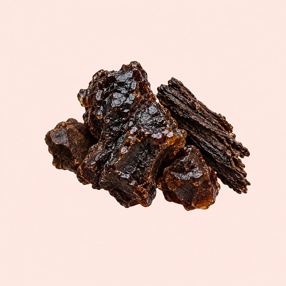 A pile of dark brown, glossy chewable pieces with a textured, bark-like surface, arranged on a solid pale pink background.