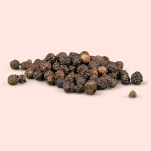 Pile of black peppercorns on a beige background