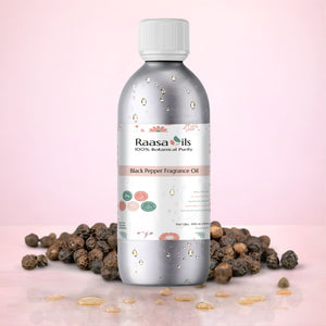 Bottle of Raasa Oils Black Pepper Fragrance Oil with black pepper seeds on a pink background