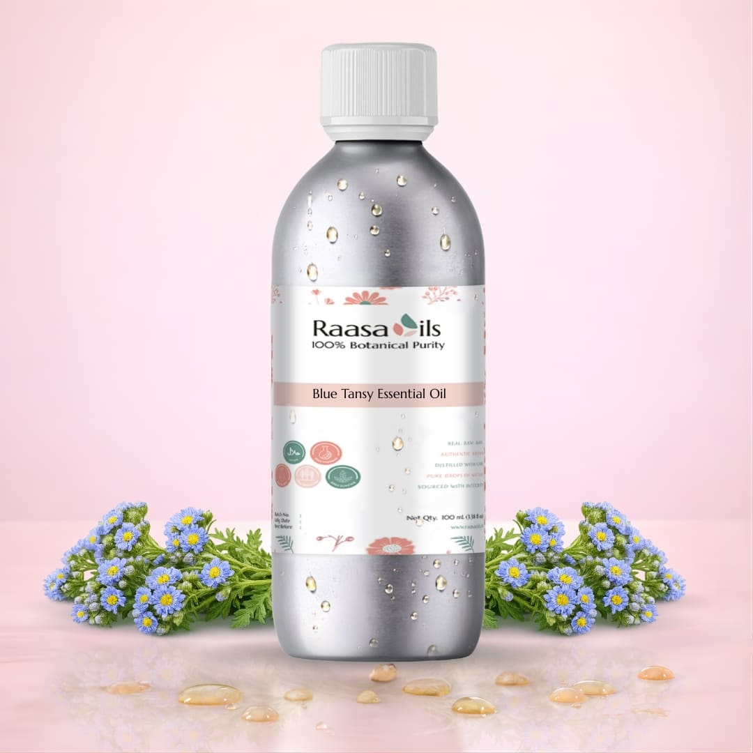 Raasa Oils Blue Tansy Essential Oil bottle with flowers on a pink background