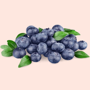 Blueberries with green leaves on a light pink background