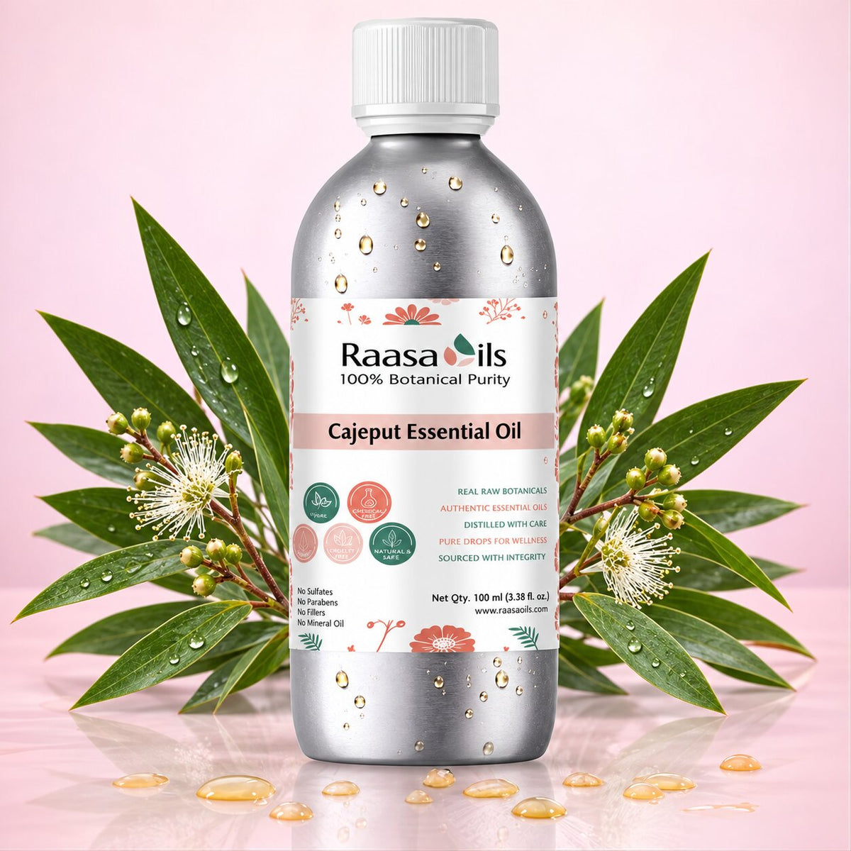 A bottle of Raasa oils Cajapeut Essential Oil centered against a soft pink background, flanked by green leaves and small white flowers with water droplets. The bottle is metallic silver with a white cap and a white label featuring pink and green botanical illustrations.