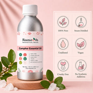 A bottle of Raasa Oils Camphor Essential Oil stands on a wooden coaster with green leaves and crystals around it, next to a pink informational graphic highlighting product benefits like 100% pure, steam distilled, undiluted, vegan, cruelty free, and no synthetic additives.