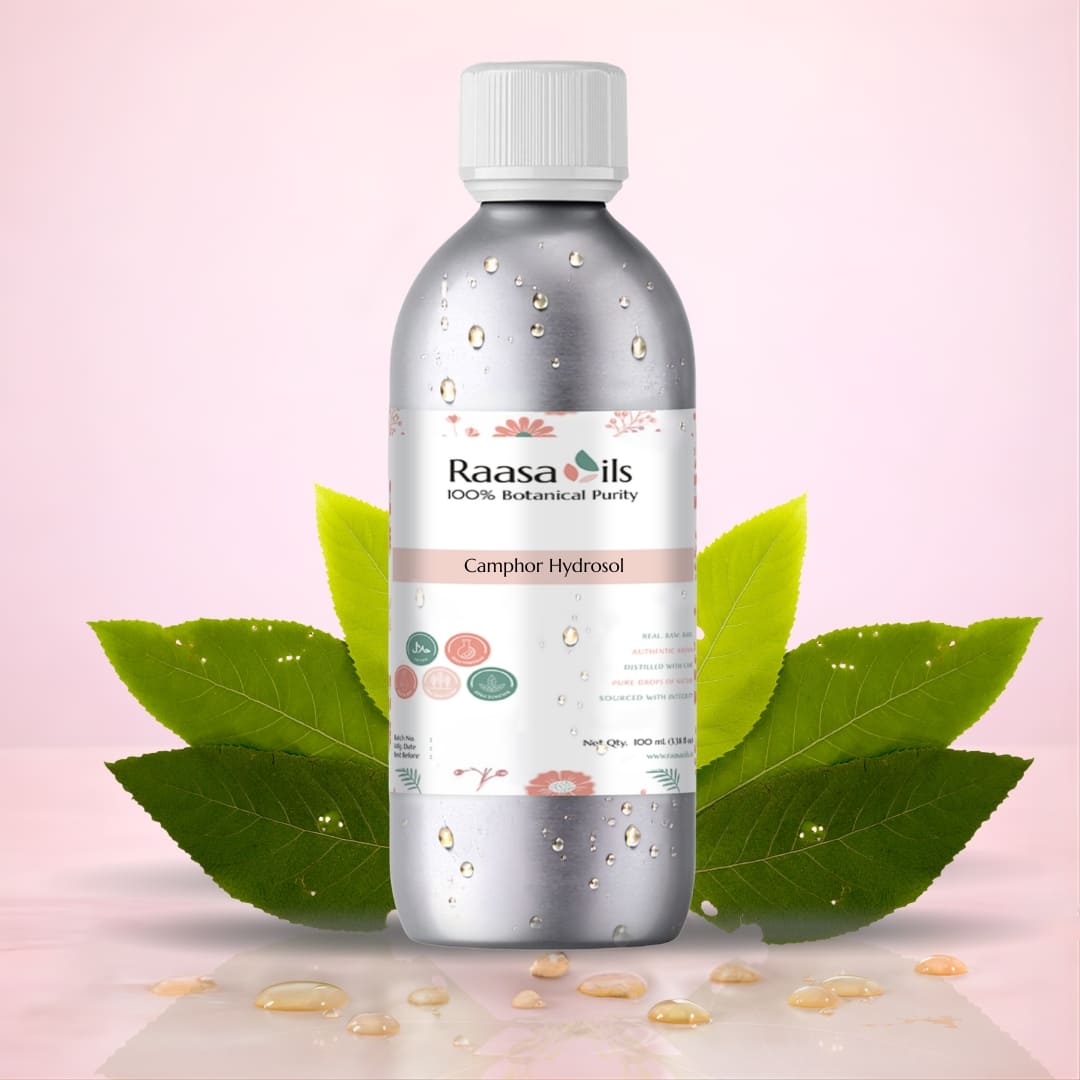 Bottle of Raasa Oils Camphor Hydrosol with green leaves on a pink background