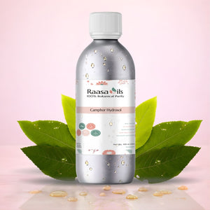 Bottle of Raasa Oils Camphor Hydrosol with green leaves on a pink background
