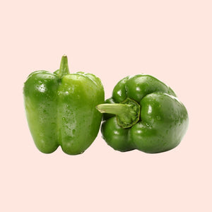 Two green bell peppers on a beige background