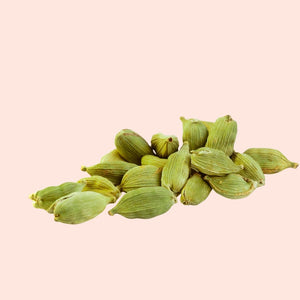 Green cardamom pods on a light pink background