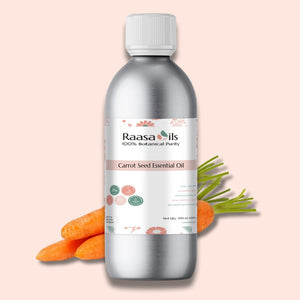 Bottle of Raasa Oils Carrot Seed Essential Oil with carrots and carrot tops on a pink background
