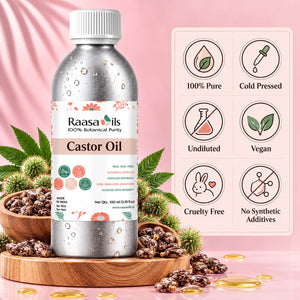 A bottle of Raasa Oils Castor Oil stands on a wooden tray with castor beans and green leaves around it, against a pink draped background. A product info panel on the right lists benefits like 100% Pure, Cold Pressed, Undiluted, Vegan, Cruelty Free, and No Synthetic Additives.