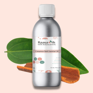 Raasa Oils Cinnamon Bark Essential Oil bottle with cinnamon bark and leaves on a light pink background