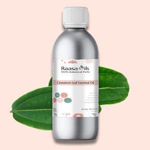 Bottle of Raasa Oils Cinnamon Leaf Essential Oil with green leaves on a pink background
