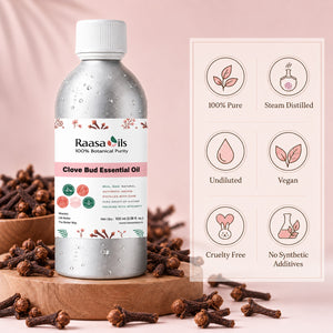 A bottle of Raasa Oils Clove Bud Essential Oil stands on a wooden tray surrounded by whole cloves, with a pink background and a product information panel showing icons for 100% pure, steam distilled, undiluted, vegan, cruelty free, and no synthetic additives.