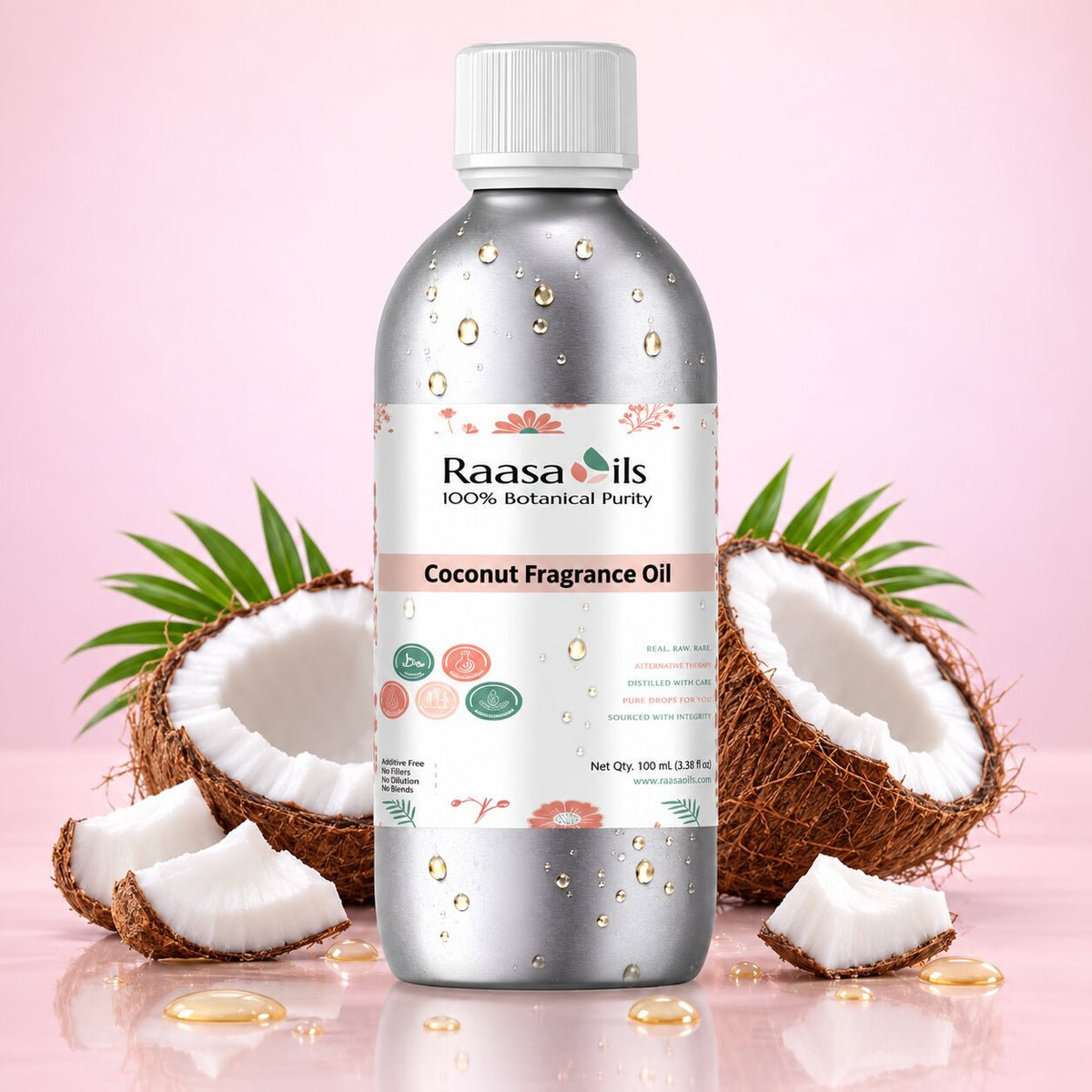 A bottle of Raasa Oils Coconut Fragrance Oil centered on a pink background, flanked by halved coconuts, coconut pieces, and a few green palm leaves. The bottle is metallic silver with a white cap and a white label featuring pink and green botanical accents.