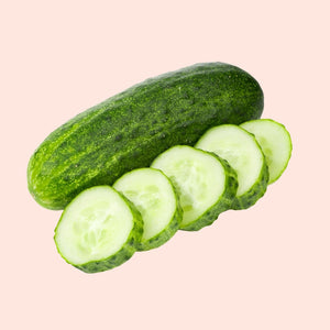 Whole cucumber and sliced cucumbers on a pink background