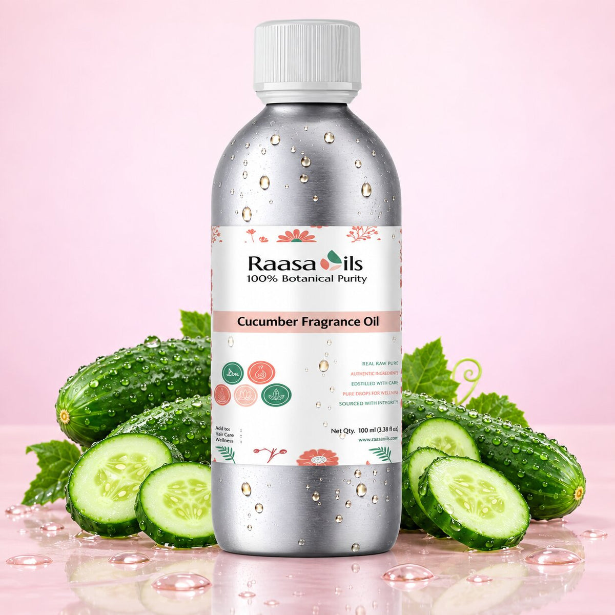 A bottle of Raasa Oils Cucumber Fragrance Oil centered on a pink background, surrounded by fresh cucumber slices, whole cucumbers, and green leaves. The bottle is metallic silver with a white cap and a white label featuring pink and green accents.