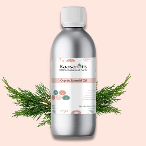 Bottle of Raasa Oils Cypress Essential Oil with a branch on a pink background