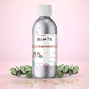 Bottle of Raasa Oils Eucalyptus Hydrosol on a pink background with eucalyptus leaves.