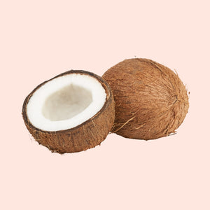 Coconut with one half cut open on a pink background
