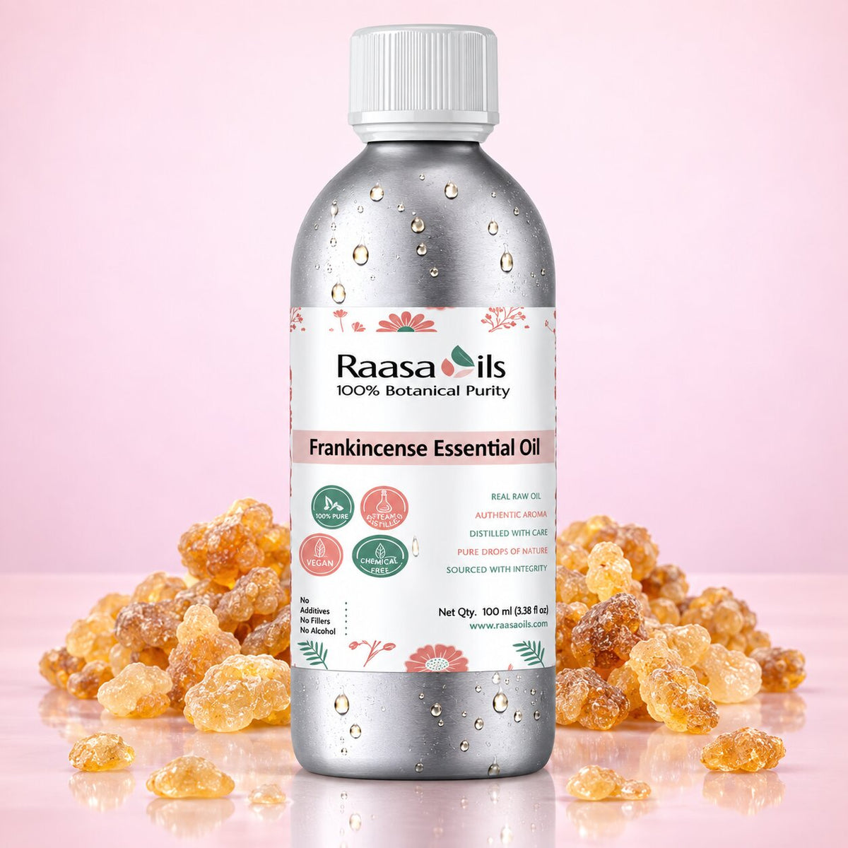 A bottle of Raasa Oils Frankincense Essential Oil centered on a pink background, surrounded by clusters of amber-colored frankincense resin. The bottle is metallic silver with a white cap and a white label featuring green and pink details.