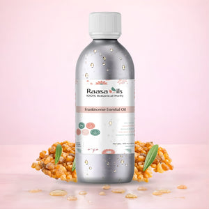 Raasa Oils Frankincense Essential Oil bottle with frankincense resin and leaves on a pink background