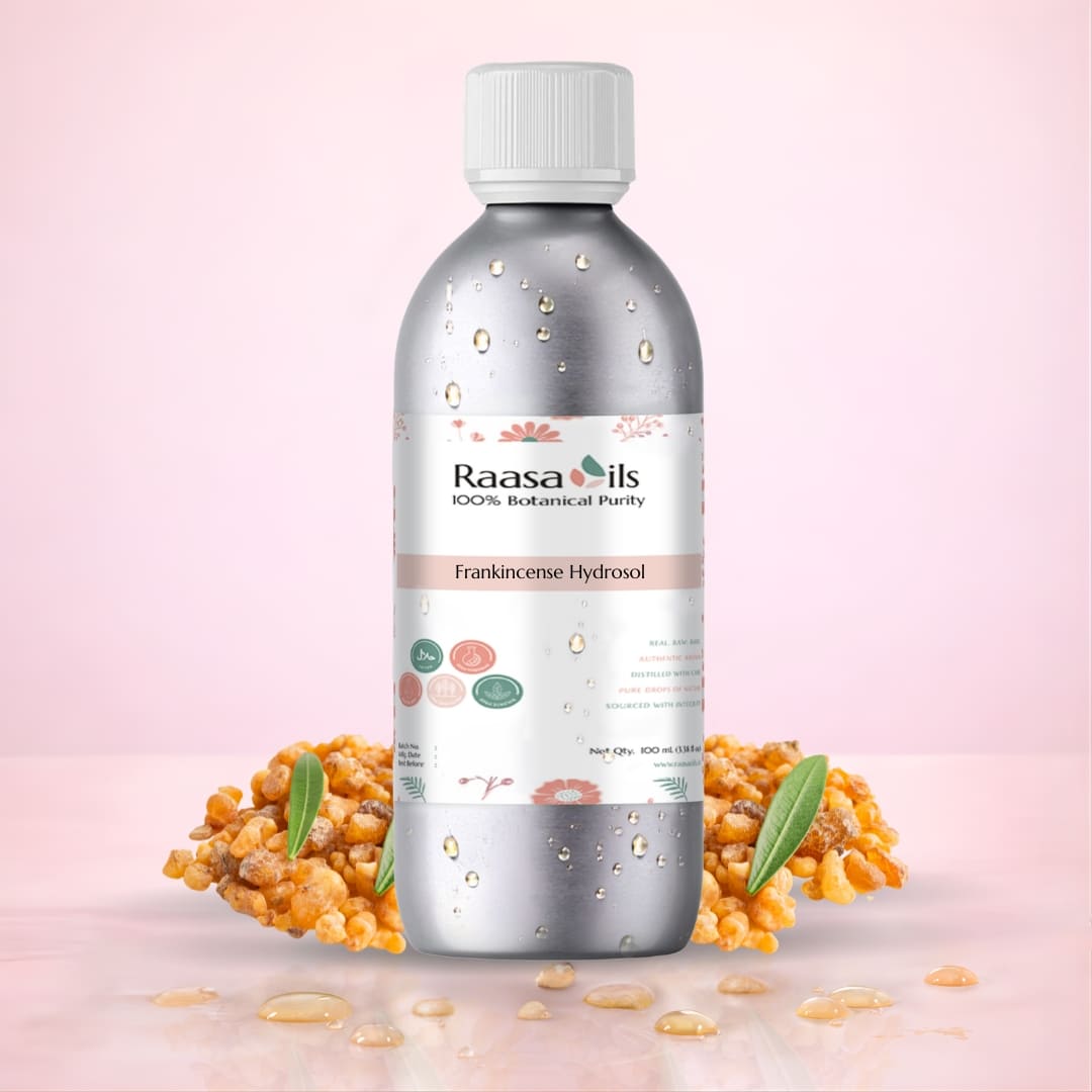 Raasa Oils Frankincense Essential Oil bottle with frankincense resin and leaves on a pink background