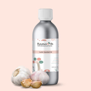 Bottle of Raasa Oils Garlic Essential Oil with garlic bulbs on a light pink background