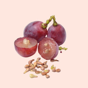 Red grapes with one halved on a pink background