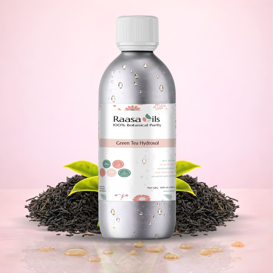 Bottle of Raasa Oils Green Tea Hydrosol with green tea leaves on a pink background