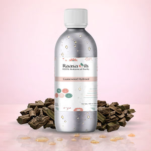 Raasa Oils bottle with guaiacwood pieces on a pink background