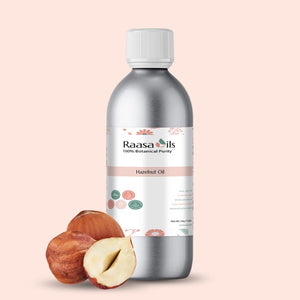 Bottle of Raasa Oils Hazelnut Oil with hazelnuts on a light pink background