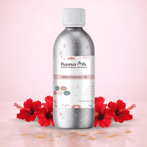 Bottle of Raasa Oils Hibiscus Fragrance Oil with red flowers on a pink background