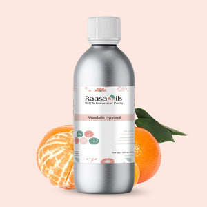 Bottle of Raasa Oils Mandarin Hydrosol with mandarin fruit and leaves on a light pink background