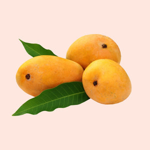 Three mangoes with green leaves on a light pink background