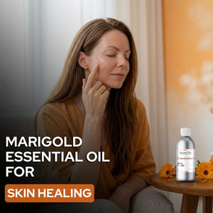 Woman applying marigold essential oil to her face with a bottle of marigold essential oil on a table.