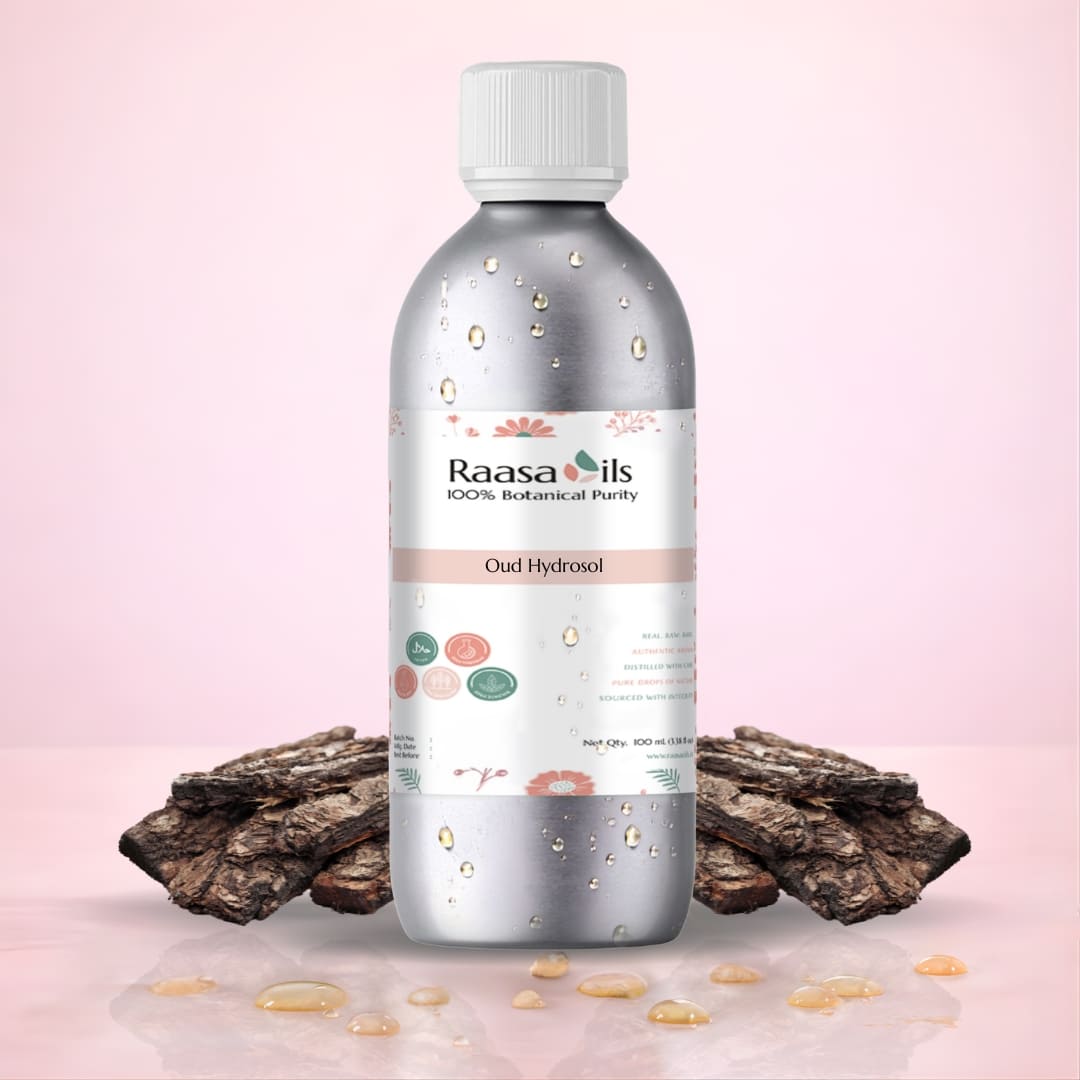 Bottle of Raasa Oils Oud Hydrosol with dried oud wood on a pink background