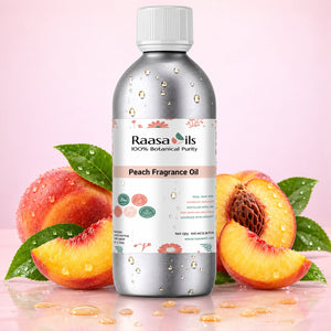 A bottle of Raasa oils Peach Fragrance Oil centered on a pink background, surrounded by fresh peach slices, whole peaches, and green leaves with water droplets. The bottle is metallic silver with a white cap and a white label featuring peach illustrations.