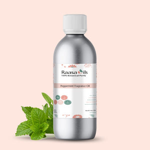 Bottle of Raasa Oils Peppermint Fragrance Oil with mint leaves on a light pink background