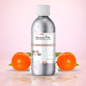 Bottle of Raasa Oils Petigrain Fragrance Oil with oranges and leaves on a pink background