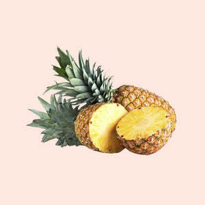 Half-cut pineapple with green leaves on a light pink background