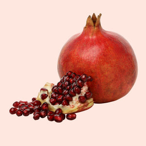 Pomegranate with a sliced open one on a light pink background