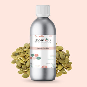 Bottle of Raasa Oils Pumpkin Seed Oil with pumpkin seeds on a pink background