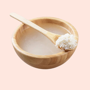 Wooden bowl with a wooden spoon holding rice on a light pink background