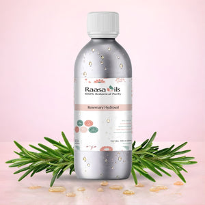 Bottle of Raasa Oils Rosemary Hydrosol with rosemary leaves on a pink background