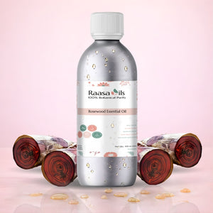 Raasa Oils Rosewood Essential Oil bottle with rosewood logs on a pink background