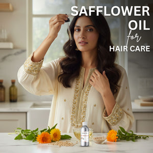 Woman with long hair holding a dropper over her head, with safflower oil and flowers on a table, in a kitchen setting.